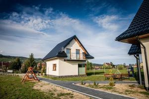 a small white house with a black roof at Prowincja Tatra Cottages in Dębno