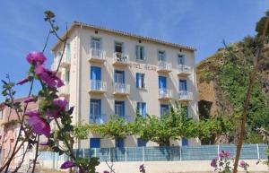 een wit gebouw met paarse bloemen ervoor bij Hôtel**résidence BEAR in Port-Vendres