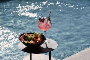 a bowl of fruit and a drink on a table by the water at SantAnna Luxury Suites in Imerovigli