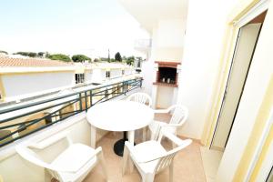 einen Balkon mit einem weißen Tisch und Stühlen in der Unterkunft Sandy Beach apartment in Albufeira