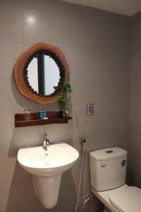 a bathroom with a toilet and a sink and a mirror at Amacon Hotel & Coffee in Buôn Kô Sir