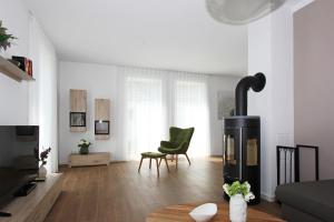 a living room with a fireplace and a green chair at Blauwasser Luv in Zingst