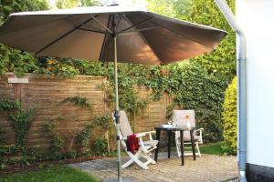 an umbrella in a garden with a table and chairs at Lieblingshaus Eddie in Prerow
