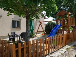 een speeltuin met een blauwe glijbaan naast een boom bij Borostyánkert Étterem & Vendégház in Sitke