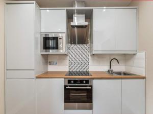 ロンドンにあるCharming 2 bedrooms Flat in Plumsteadの白いキャビネット、シンク、電子レンジ付きのキッチンが備わります。