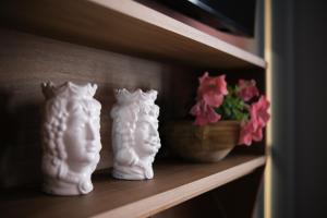 three white vases sitting on a shelf with flowers at Regina Bianca - Camere, Suite & Spa - Sciacca in Sciacca