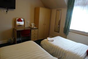 a hotel room with two beds and a desk and a window at AJ Lodge in Slough