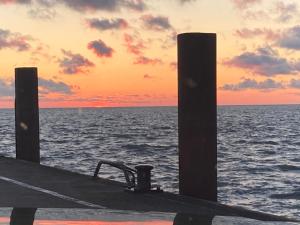 ein Dock auf dem Meer mit Sonnenuntergang im Hintergrund in der Unterkunft Hotel Die Friesenhalle in Bredstedt