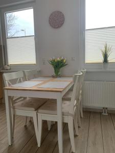 a white dining room table and chairs with flowers on it at Ferienwohnung Maximilian in Grömitz