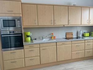 eine Küche mit Holzschränken, einer Mikrowelle und einer Spüle in der Unterkunft Ferienwohnung Maximilian in Grömitz