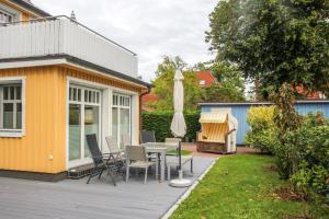 eine Holzterrasse mit einem Tisch und einem Sonnenschirm in der Unterkunft Darß Idyll in Prerow