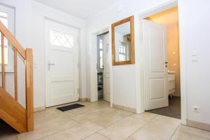 a hallway with white doors and a tile floor at Darß Idyll in Prerow +13 photos