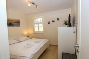 a bedroom with a white bed and a refrigerator at Darß Idyll in Prerow