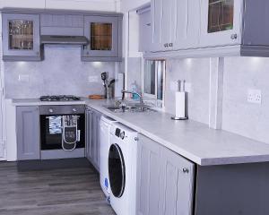- une cuisine avec des placards blancs et un lave-linge/sèche-linge dans l'établissement 5beds-2WC-2shwr-secure 2 van off-road-Biz WiFi-washer-dryer, à Corby
