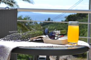un bicchiere di succo d'arancia e un libro e occhiali da sole su un tavolo di Sunčana Sara a Tučepi