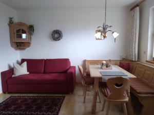 a living room with a red couch and a table at Landhaus Kirchmair in Telfes im Stubai