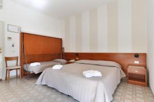 a bedroom with two beds with towels on them at Hotel Brunella in Lido di Camaiore