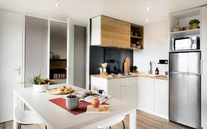 a white kitchen with a table and a refrigerator at Domaine Sainte Veziane in Bessan