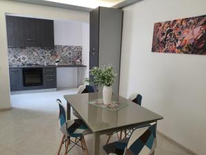 a dining room table with chairs and a vase with flowers at Appartamento Mattia in Marsala
