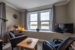 sala de estar con ventana, mesa y sillas en The Lodge in the Loch, en Portree