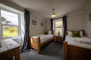 two beds in a room with two windows at The Lodge in the Loch in Portree