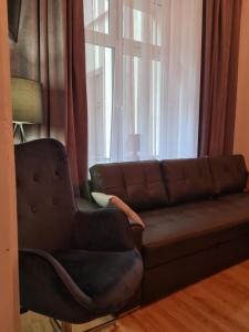 a couch and a chair in front of a window at Amber Hostel in Kraków