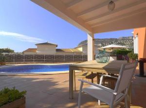 een terras met een tafel en stoelen en een zwembad bij Villa con piscina privada in Calpe