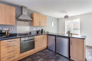 a kitchen with wooden cabinets and stainless steel appliances at Liberty House - Perfect for Contractors - 2 Off-Road Parking Spaces in Wolverhampton
