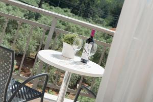 a table with a bottle of wine and glasses on a balcony at Louloudis Boutique Hotel in Skala Rachoniou