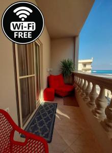 ein Wohnzimmer mit einem roten Stuhl und einem Balkon in der Unterkunft ELITE VIP - Apartment with sea VIEW - swimming pool - BBQ terrace - near BEACH in Hurghada