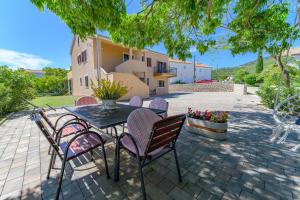 eine Terrasse mit einem Tisch und Stühlen sowie ein Gebäude in der Unterkunft Apartments Marina Veskovic in Nerezine