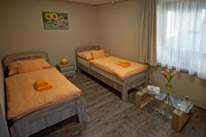 Zimmer mit 2 Betten mit orangefarbener Bettwäsche und einem Tisch in der Unterkunft Bodzaház Apartman in Tarján