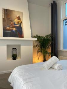 uma cama branca num quarto com uma pintura na parede em Hidden Gem next to TU Delft Campus Family XL house em Delft