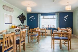 een restaurant met houten tafels en stoelen en een blauwe muur bij The Royson Guest House in Shanklin