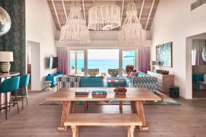 ein Wohnzimmer mit einem Tisch und Meerblick in der Unterkunft Finolhu Baa Atoll Maldives in Baa-Atoll