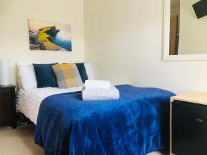 a bedroom with a bed with a blue blanket at Feochan Rooms Portree in Portree