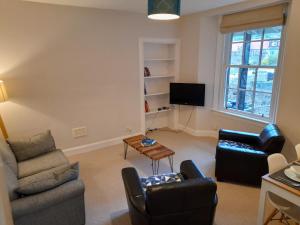 uma sala de estar com duas cadeiras e uma televisão em Burntisland Garden Apartment, Fife - 40 mins to Edinburgh em Burntisland