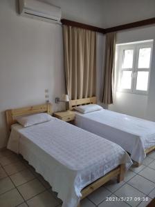 two beds in a hotel room with a window at Paradisos Kastellorizou in Meyisti