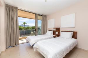 duas camas num quarto de hotel com uma grande janela em Apartamentos Vila das Lagoas – Salgados na Guia