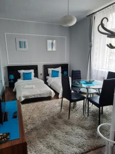 1 dormitorio con 2 camas, mesa y sillas en Sleep Well, en Poznan