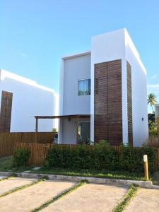 Casa duplex de temporada em Imbassai في ايمباسّاي: منزل أبيض كبير مع سور خشبي