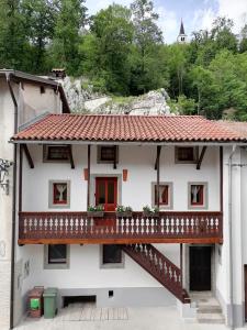 uma casa branca com uma varanda e uma escadaria em Hiša pod Gradičem em Kobarid