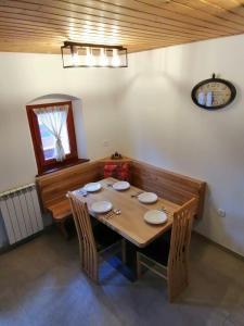 uma mesa de jantar com cadeiras e um relógio na parede em Hiša pod Gradičem em Kobarid