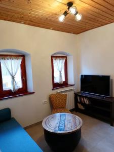 uma sala de estar com um sofá, uma mesa e uma televisão em Hiša pod Gradičem em Kobarid