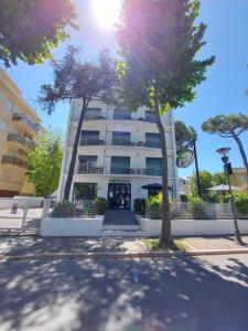 un edificio alto y blanco con árboles delante en Hotel Senza Pensieri Riccione, en Riccione