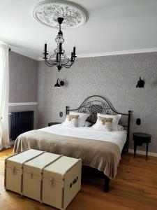 1 dormitorio con 1 cama grande y lámpara de araña en La Belle Epoque, en Kerlaz