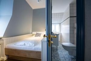 a small bedroom with a bed and a toilet at Ual Öömrang Wiartshüs in Norddorf +129 photos