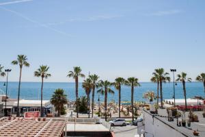 een uitzicht op een strand met palmbomen en de oceaan bij Spacious 200 sq.m. penthouse with sea view terraces in Torremolinos