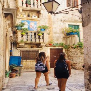 two women walking down a street in front of a building at Hurricane Hostel in Split