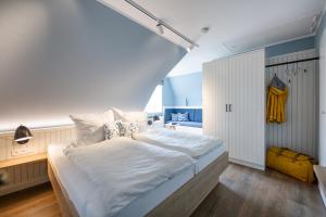 a bedroom with a large bed with white sheets at Ual Öömrang Wiartshüs in Norddorf